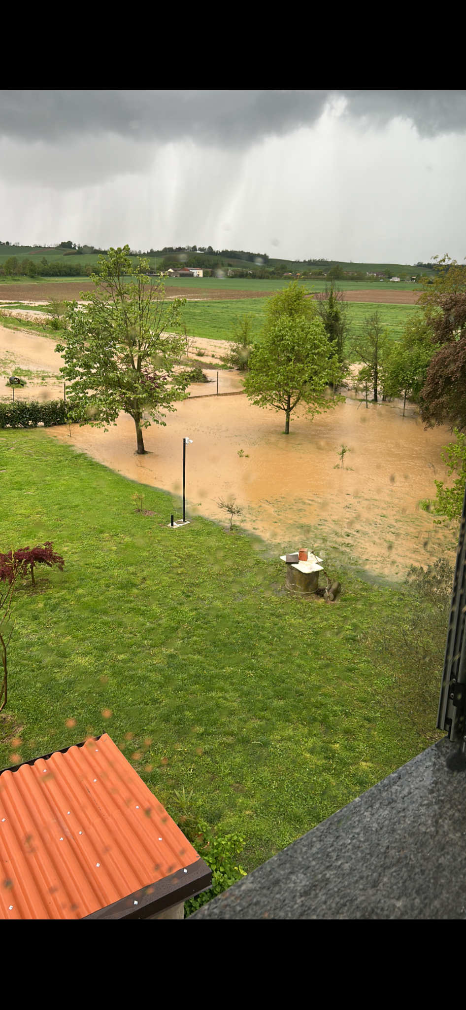 Floodwater across a Monferrato garden and neighbouring fields after intense rain